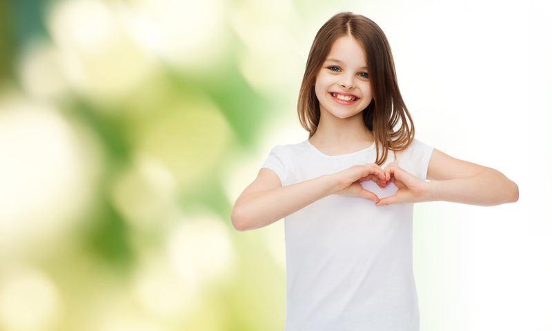 smiling little girl making heart-shape gesture with hands