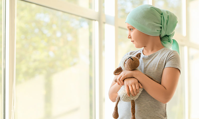 Little girl with cancer holding a stuffed animal.