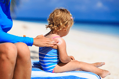 Little girl with her mom putting sunscreen on her