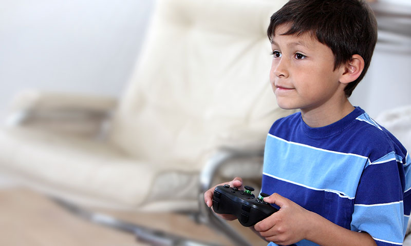 Little boy playing video game holding Xbox controller