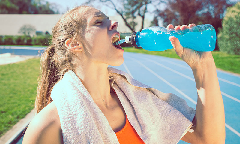 female teen athlete drinking sports drink on track