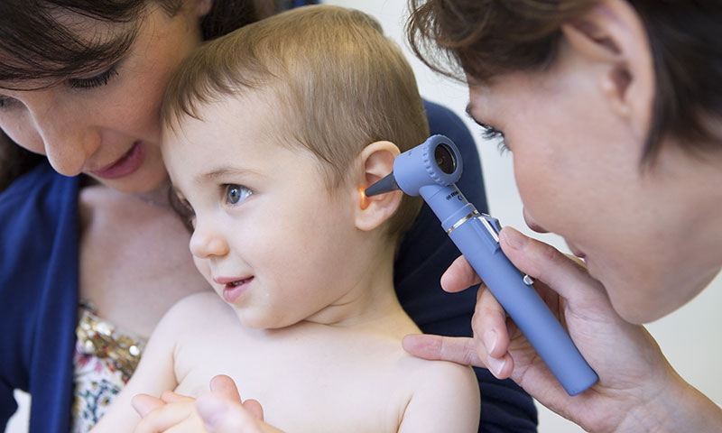 little boy held by mother getting ear examined