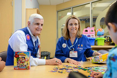 volunteers working on puzzle with little boy inpatient
