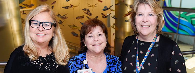 Jenny S. (Clinical Social Worker), Catherine S. (Team Leader Social Work), and Laurie W. (Manager Social Work) posing in the butterfly atrium