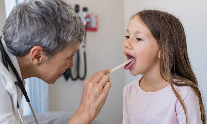 Doctor examining little girl's throat